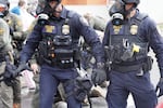 Department of Homeland Security police, along with other federal police, push and tackle protesters at the Immigration and Customs Enforcement facility south of downtown Portland on Sunday, Oct. 12, 2025.
