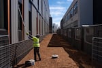 Frank Alaebo, a cleaner with the construction crew working for the new school, cleans windows on the new building. A section of the old building, slated to be demolished, stands at the left.