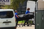 The body of the shooting suspect is placed in the medical examiners van outside the apartment building near the scene of a shooting at a U.S. Immigration and Customs Enforcement office in Dallas on Wednesday, Sept. 24, 2025.