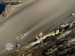 Several people with headlamps surround an injured woman on Mount Hood as night falls