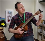 Librarian Brendan Lax tunes newly donated ukuleles to make sure they are ready for checkout.