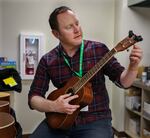 Librarian Brendan Lax tunes newly donated ukuleles to make sure they are ready for checkout.