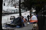 A pedestrian walks down a sidewalk in Portland, Oregon, that has tents on both sides of it.