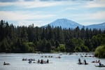 People on small non-motorized boats float on a river.