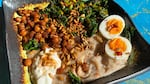 A comforting bowl of savory porridge topped with harissa greens, spiced sunflower seeds, crispy garbanzos and a jammy egg.