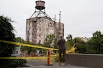 A pedestrian takes photos of the burned building. The Fields Park, which is across the railroad from the structure, is closed to the public for safety.