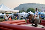 Kimberly Venable, 11, of Alfalfa, Ore., rides the mechanical bull at the Crook County Fair in Prineville, Ore., on Aug. 5, 2026. Venable and her mother had debated coming out because of the wildfire smoke, but the air improved through the day, and she was glad to make it out for the ride.