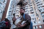 A man carries his dog in front of a residential multi-story building damaged after a Russian drone strike on Kyiv, Ukraine on Friday.