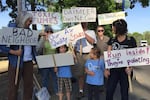 Neighbors of the Daimler Trucks manufacturing facility on Swan Island in Portland hold protest signs outside the company's new headquarters building.