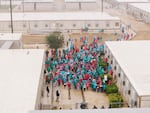 FILE - People held at the South Texas Family Residential Center wave signs during a demonstration in Dilley, Texas, Jan. 24, 2026. Reports of inadequate food and water at the facility have been widespread.
