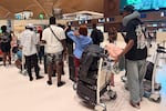 A group of Ugandan men and women line up to board their flight back home, after being released from scam compounds in Cambodia and then enduring compounding hardship on the streets of Phnom Penh.