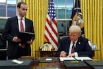 President Donald Trump signs an executive order to create the Department of Government Efficiency (DOGE) in the Oval Office of the White House, Monday, Jan. 20, 2025, in Washington, as White House staff secretary Will Scharf watches. Of the executive orders signed by Trump on Monday, one of them was to end birthright citizenship.