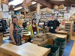 Employees Eva Sway, Lucina Woods and Eli Ari pose at Sundance Natural Foods on April 22, 2024, in Eugene, Ore.  Employees at Sundance receive health care benefits, profit-sharing checks, and discounts on food and supplements. Through a perpetual purpose trust, the company's long-term leader hopes to preserve a sense of culture at the store.