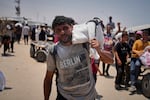 Omar al-Hobi, 43, from Rafah, carries a bag of food he collected at a distribution center run by private contractor the Gaza Humanitarian Foundation in the southern Gaza Strip, as he arrives at his tent in Khan Younis, on June 10.