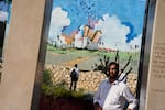 Three men visit a memorial at a police station attacked by Hamas on October 7, 2023, in Sderot, southern Israel, on October 4, 2026. The memorial includes a large mural of a white building with a giant Torah scroll on top of it.