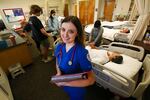 A female nursing student poses in a hospital room.