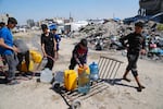 Young Palestinians fill cans with water in Jabaliya, northern Gaza Strip, on Sunday. Arab negotiators are trying to broker a ceasefire deal that would avert a return to fighting in Gaza and begin serious negotiations toward a formal end of the war, since the breakdown of the Israel-Hamas ceasefire deal at the beginning of the month.