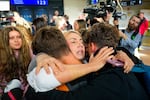 A family hugs after disembarking from an evacuation flight on a commercial airplane from Muscat, Oman, at the Henri Coanda International Airport in Otopeni, Romania.