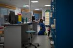 A nurse rests her knees on the floor as she looks at a computer screen during the day shift at the COVID-19 ICU of the La Timone hospital in Marseille, southern France, Thursday, Nov. 12, 2020.