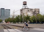 A cyclist crosses the train tracks near the Centennial Mills building on Aug. 10, 2026, in Portland, Ore. Demolition is set to start on the building on Aug. 14, after a fire made the structure unsafe.