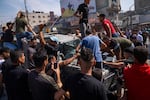 Palestinians gather around an Israeli army vehicle that Palestinian militants drove from Israel into Gaza, in Shejaiya, Gaza Strip, Saturday, Oct. 7, 2023.