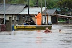 Police officers check a house as residents wade through a flooded street after floods caused by a cyclone in Passo Fundo, Rio Grande do Sul state, Brazil, Monday.