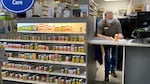 A pharmacist fills out paperwork behind a counter that's next to a shelf full of vitamins and medicines.