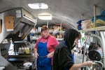 (Left to right) Amanda Ames checks on her employee, Max Haney, while she washes dishes in the Ames Meat Research food cart in Portland, Ore., July 15, 2025. Temperatures are expected to reach well over 90 degrees for the next few days, and Oregonians are attempting to stay cool in whatever ways they can. 