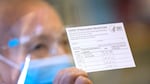 A person hold a COVID-19 vaccine card up.