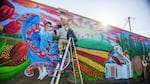 Muralist Hector H. Hernandez puts finishing touches on a mural on the side of the Woodburn Independent newspaper building in downtown Woodburn, Oregon.