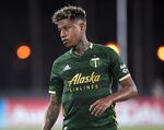 A male player wearing a green Portland Timbers soccer shirt that reads "Alaska Airlines" plays soccer.
