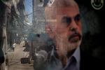 People are reflected in a window displaying a poster of Hamas leader Yahya Sinwar in the Palestinian camp of Bourj al-Barajneh, on Aug. 8, in Beirut.