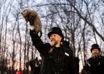 Punxsutawney Phil is held in the air by a man with a top hat.