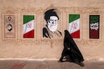 A woman walks past a mural depicting Iran's late supreme leader, Ayatollah Ali Khamenei, at Valiasr Square in central Tehran, on Aug. 8.