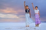 Isabella and Alyssa Klain raise their fists in the air on the salt flats outside their home in Salt Lake City, Utah.