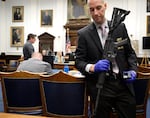 FILE - Kenosha Police Department Detective Martin Howard, right, picks up the weapon Kyle Rittenhouse used on Aug. 25, 2020, during Rittenhouse's trial at the Kenosha County Courthouse in Kenosha, Wis., on Nov. 8, 2021. A Wisconsin judge on Friday, Jan. 28, 2022, approved an agreement by lawyers to destroy the assault-style rifle that Rittenhouse used to shoot three people during a 2020 street protest.