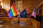 A Pride flag, Oregon flag and U.S. flag rest on a desk in the Oregon Capitol. The Oregon Department of Human Services has narrowed protections under Oregon rules for ensuring LGBTQ+ foster youth have inclusive placements.