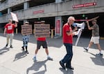 Picketers march on the sidewalk in front of the Garden Garage parking structure, attached to the Moda Center.