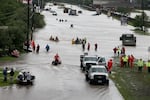 People make their way out of a flooded neighborhood in Houston after it was inundated with rain during 2017's Hurricane Harvey.