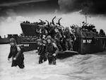Reinforcements disembark from a landing barge at Normandy during the Allied invasion of France on D-Day.