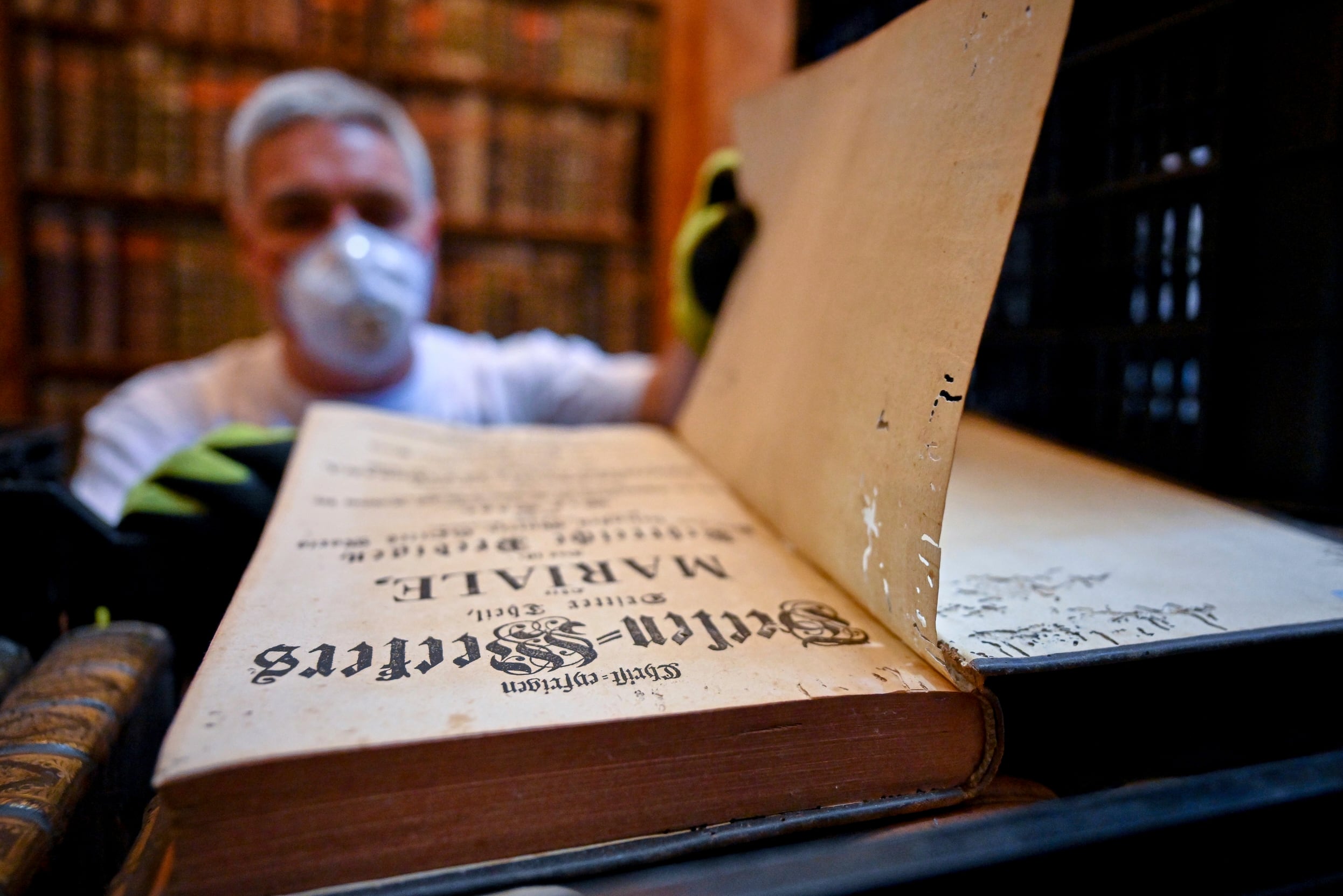 In this photo provided by Pannonhalma Archabbey, a restorer shows an old book with holes in its pages due to a drugstore beetle infestation, at the Pannonhalma Archabbey's library in Pannonhalma, Hungary on July 3.