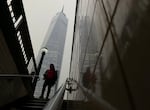 A commuter steps into the subway as smoke from wildfires in Canada partially obscure One World Trade Center in lower Manhattan, Tuesday, June 6, 2023, in New York.
