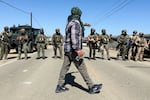 A demonstrator walks in front of federal agents blocking a road during an immigration raid in Camarillo, Calif., Thursday, July 10, 2025.