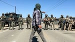 A demonstrator walks in front of federal agents blocking a road during an immigration raid in Camarillo, Calif., Thursday, July 10, 2025.