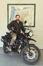 Elijah Curran poses for a photo while riding his motorcycle at his parents' home in Bend on June 14, 2026. Elijah Curran, a Bend geologist and travel writer, is embarking on a two-year round-the-world road trip by motorcycle, visiting 64 countries on six continents.