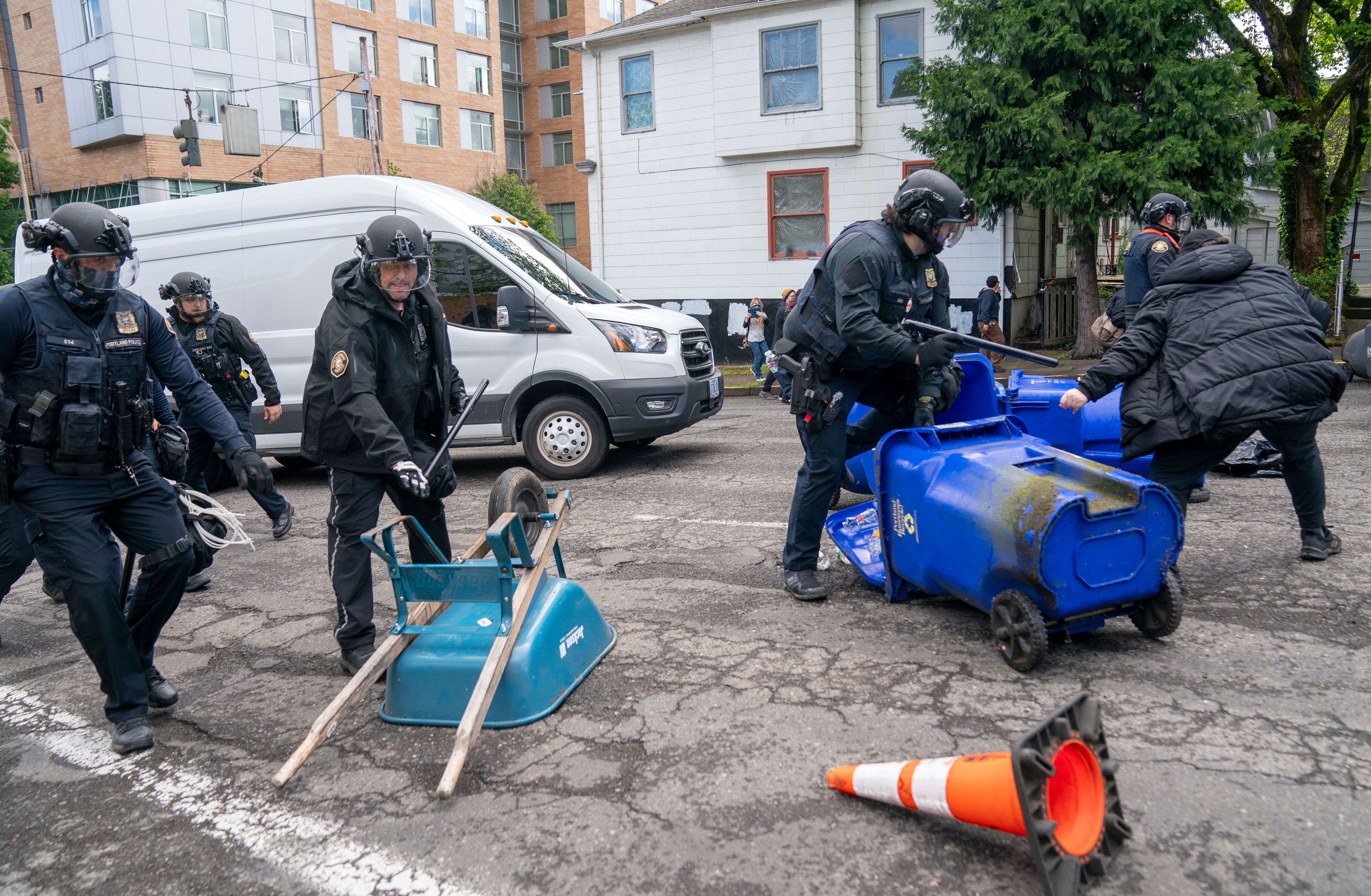 Law enforcement teams remove debris on Southwest Broadway to allow passage of a van carrying detained protesters from Portland State University’s Branford Price Millar Library, May 2, 2024. People protesting Israel's role in the war in Gaza had occupied the library since Monday evening.