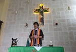 Rev. Elaine Saralegui, wearing a rainbow-colored clergy stole and her clerical collar, welcomes congregants to a service at the Metropolitan Community Church, an LGBTQ+ inclusive house of worship, as Ruth the dog stands with her front paws on the altar table, in Matanzas, Cuba, Friday, Feb. 2, 2024. In 2015, with support from the U.S.-based LGBTQ+ affirming Metropolitan Community Churches, they converted a house into their church, decked with wooden pews and a stained-glass cross that hangs above the altar.