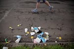 A runner passes by a pile of cups and gel wrappers during the Portland Marathon in Portland, Ore., Sunday, Oct. 6, 2019. The marathon's new route traveled through the Sellwood neighborhood.