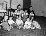 FILE - Oregon farmer Harry Holt, top center, poses with eight Korean-American orphans who he will adopt and four other orphans for other American families, in Seoul, South Korea, Oct. 13, 1955. Next week Holt will board an airliner with all 12 of them that will bring them to their new homes and families in the U.S.