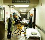 Medical crews move a patient on a hospital bed.
